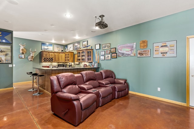 living area with baseboards, bar, and finished concrete floors