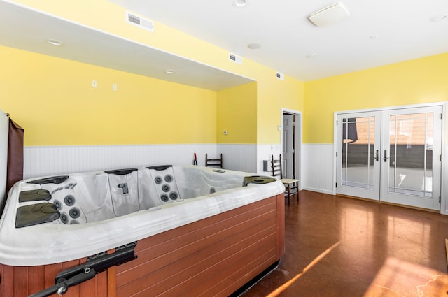 interior space featuring french doors, a wainscoted wall, finished concrete flooring, light countertops, and visible vents