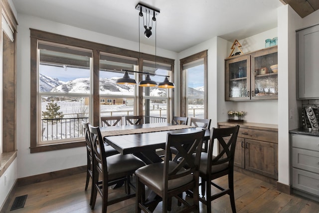 dining room with dark wood-type flooring, visible vents, a mountain view, and baseboards