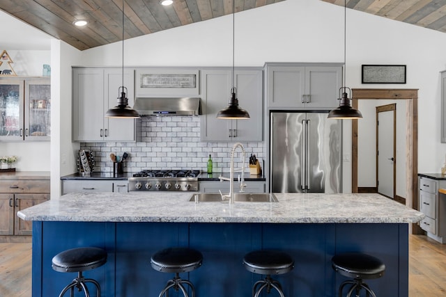 kitchen with high end refrigerator, lofted ceiling, light stone counters, a breakfast bar area, and pendant lighting