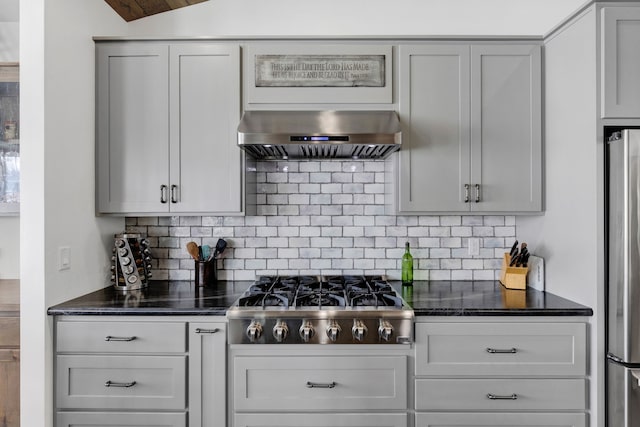 kitchen featuring tasteful backsplash, range hood, stainless steel appliances, and dark stone countertops