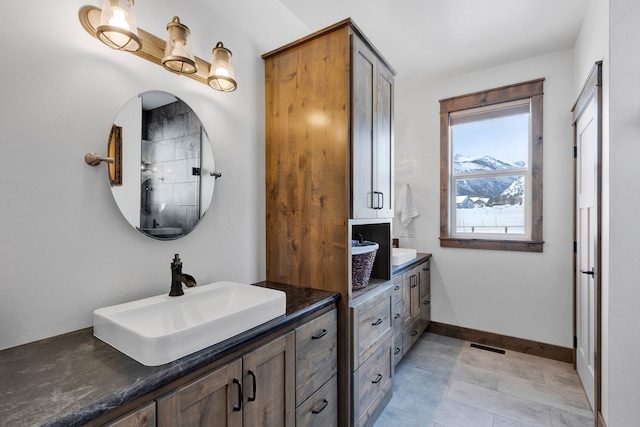 full bathroom featuring two vanities, a sink, and baseboards