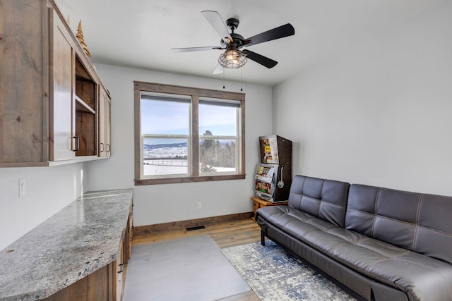 living area with a ceiling fan, visible vents, light wood-style flooring, and baseboards