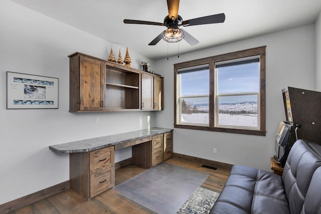 home office with dark wood-type flooring, built in study area, visible vents, and baseboards