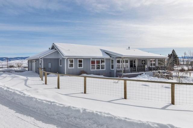 view of front facade featuring board and batten siding, covered porch, fence, and a garage