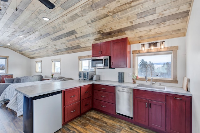 kitchen featuring stainless steel appliances, a peninsula, a sink, open floor plan, and light countertops