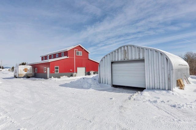 snow covered structure with an outbuilding