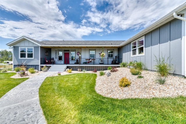 single story home with board and batten siding, a porch, and a front lawn