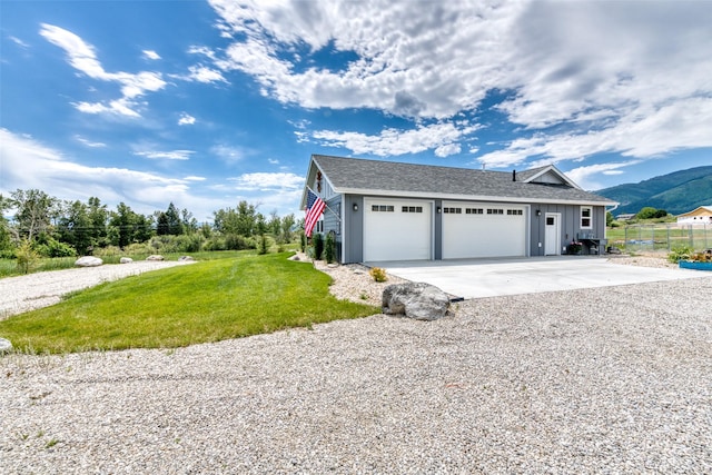 view of front facade with board and batten siding, a front yard, a mountain view, a garage, and driveway