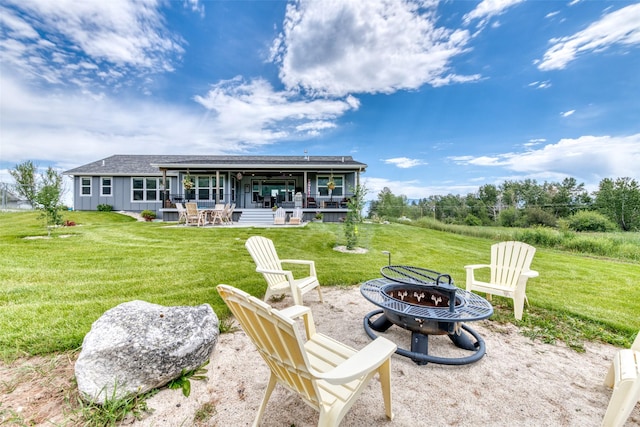 rear view of house with roof with shingles, a lawn, board and batten siding, an outdoor fire pit, and a patio area