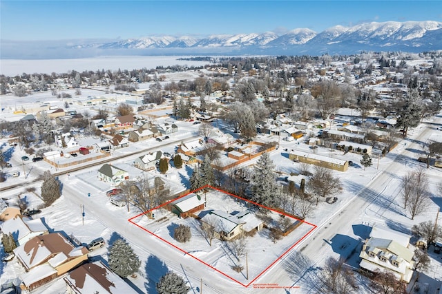 snowy aerial view featuring a residential view and a mountain view