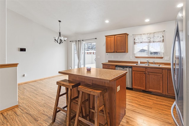 kitchen featuring pendant lighting, brown cabinets, stainless steel appliances, a kitchen island, and a kitchen breakfast bar