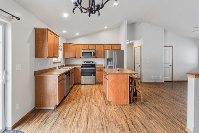 kitchen with appliances with stainless steel finishes, a center island, light countertops, and a kitchen breakfast bar