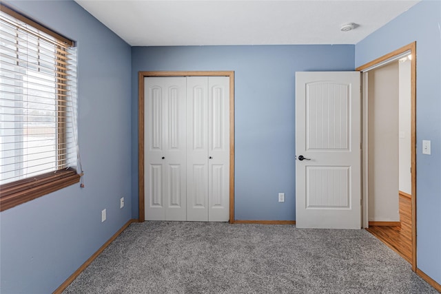 unfurnished bedroom featuring carpet floors, multiple windows, baseboards, and a closet