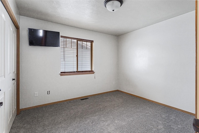 empty room with a textured ceiling, carpet, visible vents, and baseboards