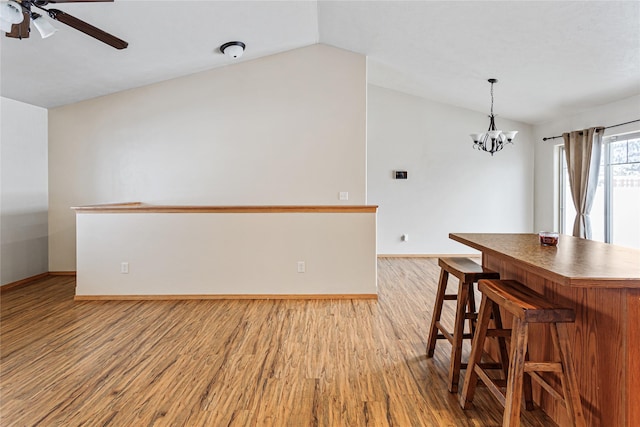 dining space with light wood-style floors, lofted ceiling, and baseboards