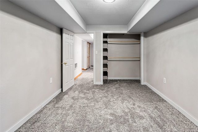 unfurnished bedroom featuring a textured ceiling, carpet floors, visible vents, baseboards, and a closet