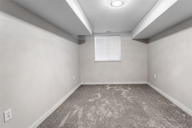 finished basement with visible vents, a textured ceiling, baseboards, and carpet flooring