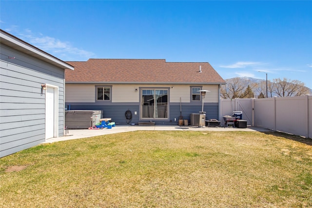 back of house featuring a hot tub, a patio, a fenced backyard, and a yard