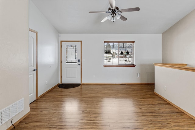 empty room with baseboards, visible vents, a ceiling fan, lofted ceiling, and wood finished floors