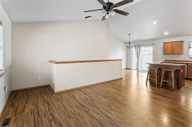 interior space with dark wood-style floors, brown cabinets, visible vents, and a kitchen bar