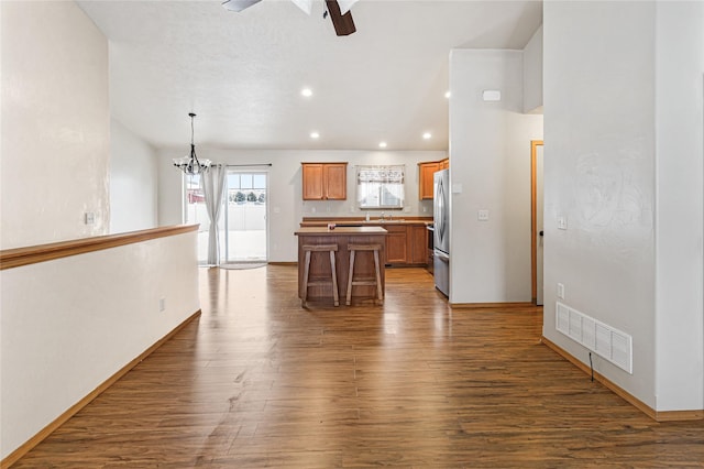 kitchen featuring freestanding refrigerator, visible vents, hanging light fixtures, and wood finished floors