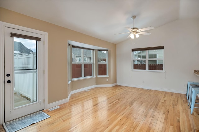 interior space with lofted ceiling, light wood finished floors, visible vents, and baseboards