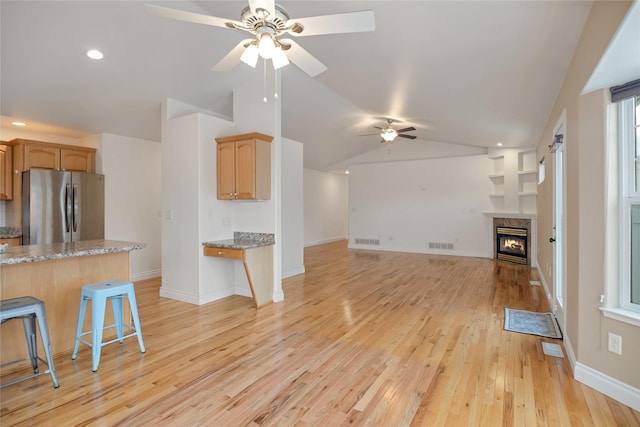 kitchen with lofted ceiling, visible vents, freestanding refrigerator, open floor plan, and a kitchen breakfast bar