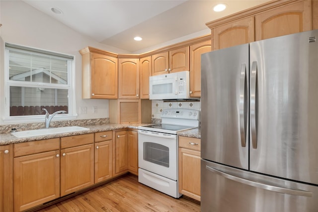 kitchen with white appliances, light stone counters, light wood-type flooring, light brown cabinets, and a sink