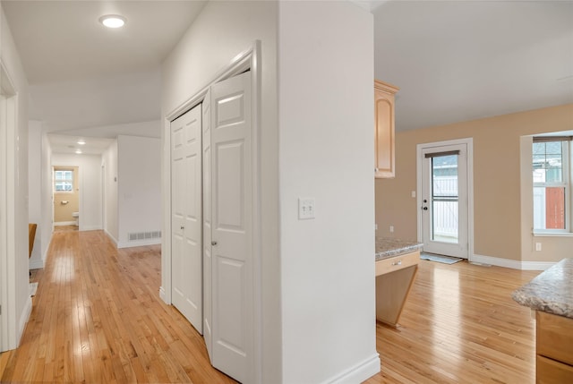 hallway with light wood-style flooring, visible vents, and baseboards