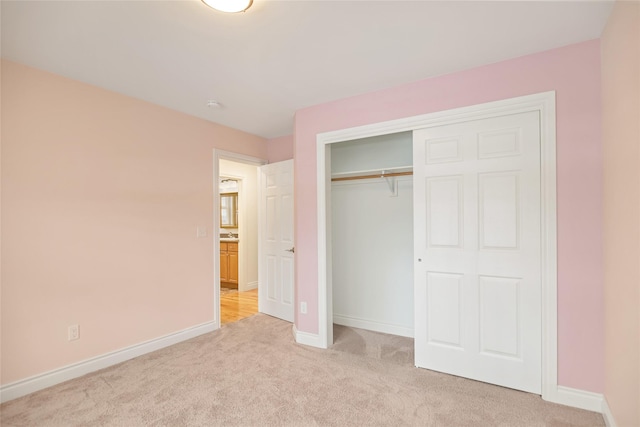 unfurnished bedroom featuring baseboards, a closet, and light colored carpet