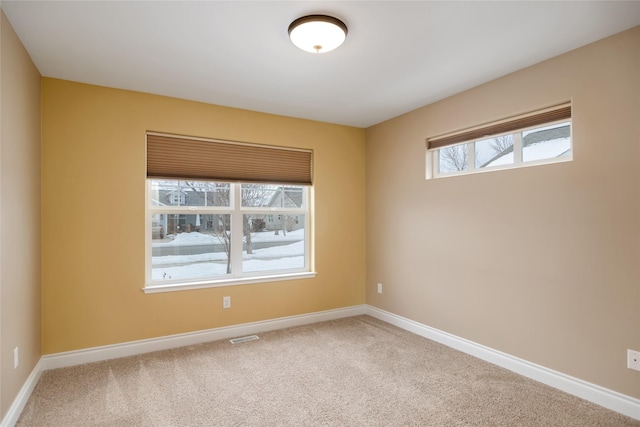 carpeted spare room with visible vents and baseboards