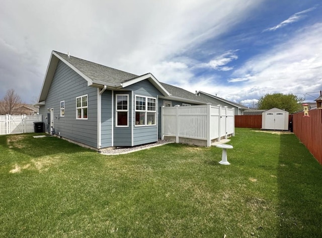 rear view of property with a storage shed, a lawn, an outbuilding, and a fenced backyard