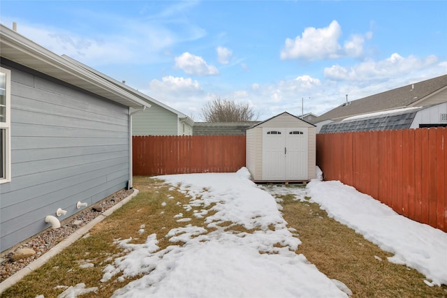 yard layered in snow with a storage shed, a fenced backyard, and an outdoor structure