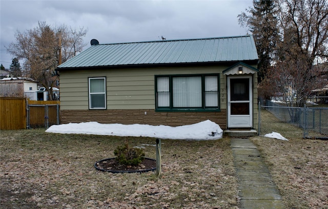 view of front facade featuring stone siding, fence, and metal roof