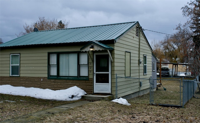 view of front of house with stone siding, metal roof, and fence