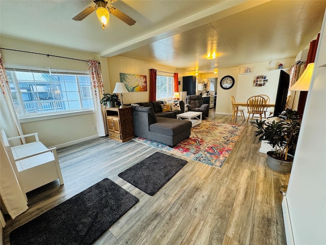 living room with a ceiling fan, baseboards, and wood finished floors