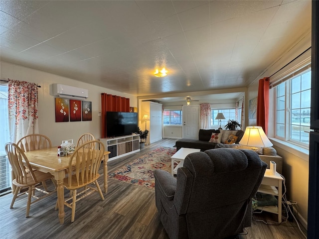 living area featuring a wall mounted air conditioner, dark wood finished floors, a ceiling fan, and baseboards