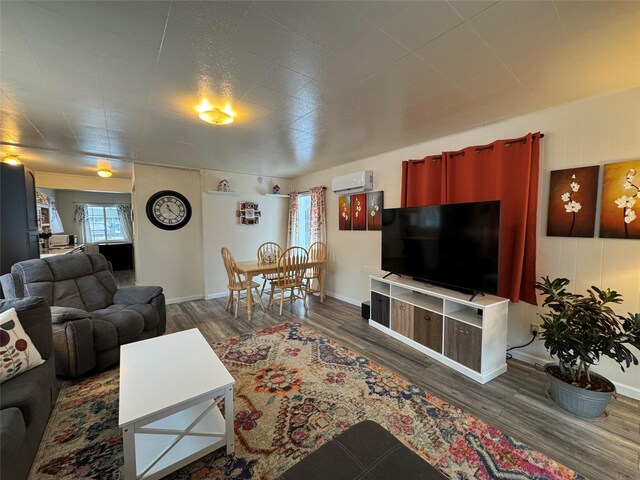 living room with a wall mounted AC, wood finished floors, and baseboards