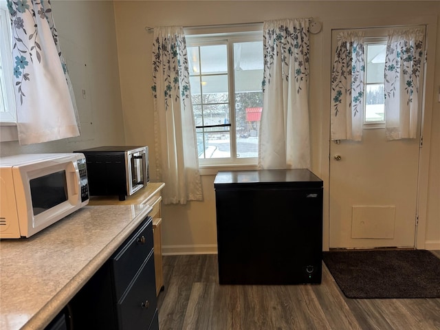 kitchen featuring white microwave, refrigerator, light countertops, stainless steel microwave, and dark wood finished floors