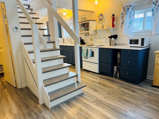 kitchen with white appliances, a sink, light wood-style floors, light countertops, and open shelves