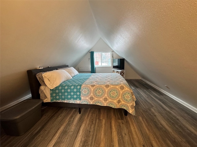 bedroom with vaulted ceiling, a textured ceiling, baseboards, and wood finished floors