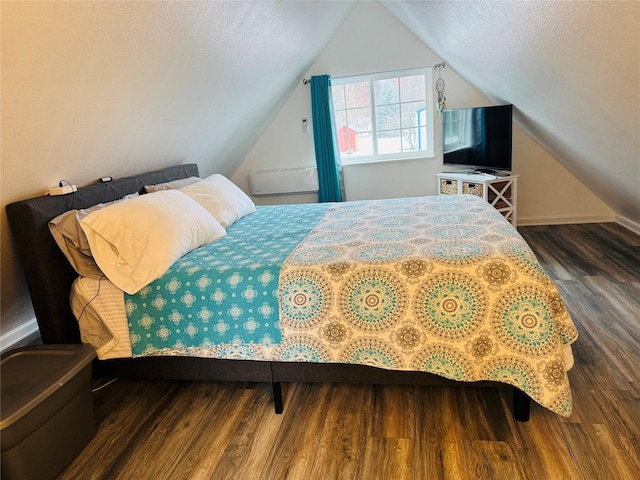 bedroom with vaulted ceiling, a textured ceiling, and wood finished floors