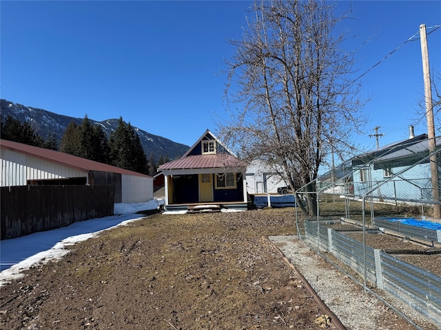 view of front of house featuring a mountain view, metal roof, an outdoor structure, and fence