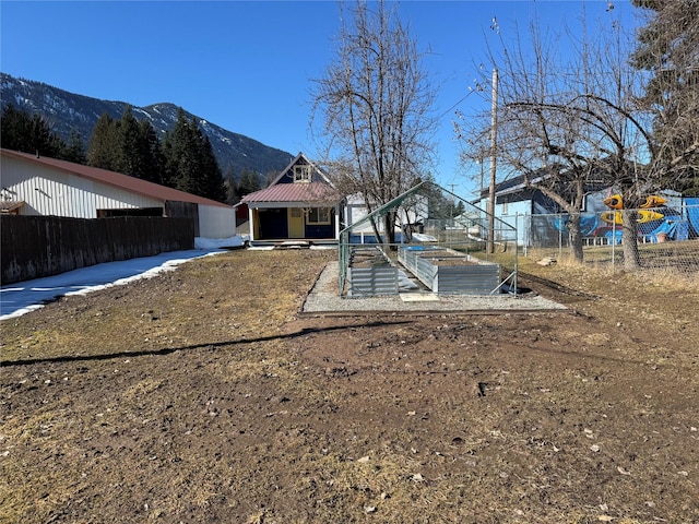 view of yard featuring a garden, fence, a mountain view, and an outdoor structure