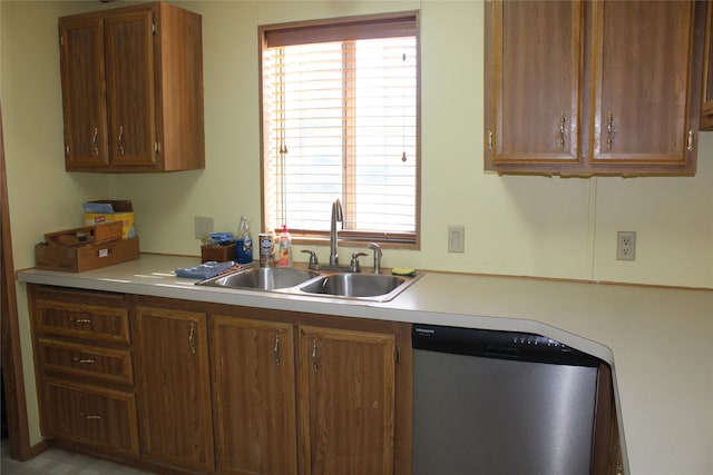 kitchen with a sink, brown cabinetry, light countertops, and stainless steel dishwasher