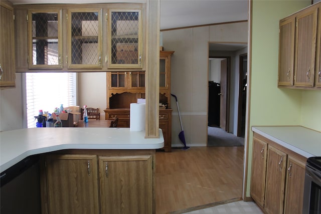 kitchen with light countertops, brown cabinetry, glass insert cabinets, and crown molding