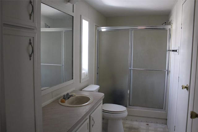 bathroom with tile patterned floors, a shower stall, toilet, and vanity