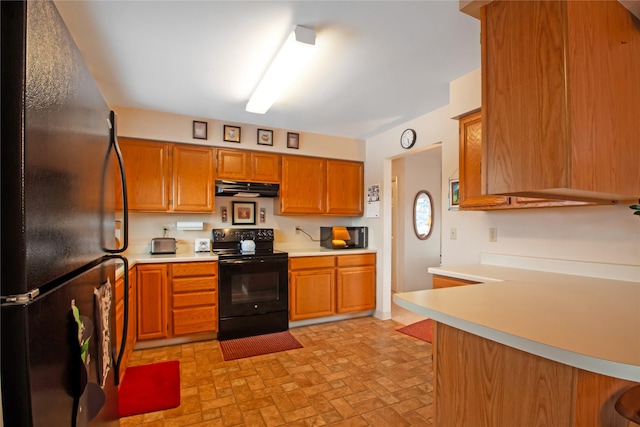 kitchen with brown cabinets, black appliances, under cabinet range hood, and light countertops