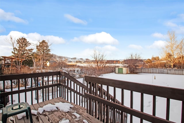 snow covered deck featuring fence and stairs